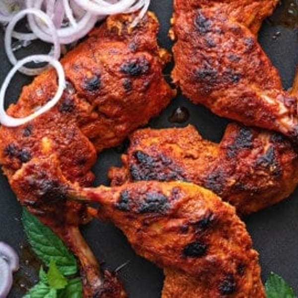 Close-up of Bawarchi Biryanis' Indian chicken wings, garnished with mint and sliced onions.